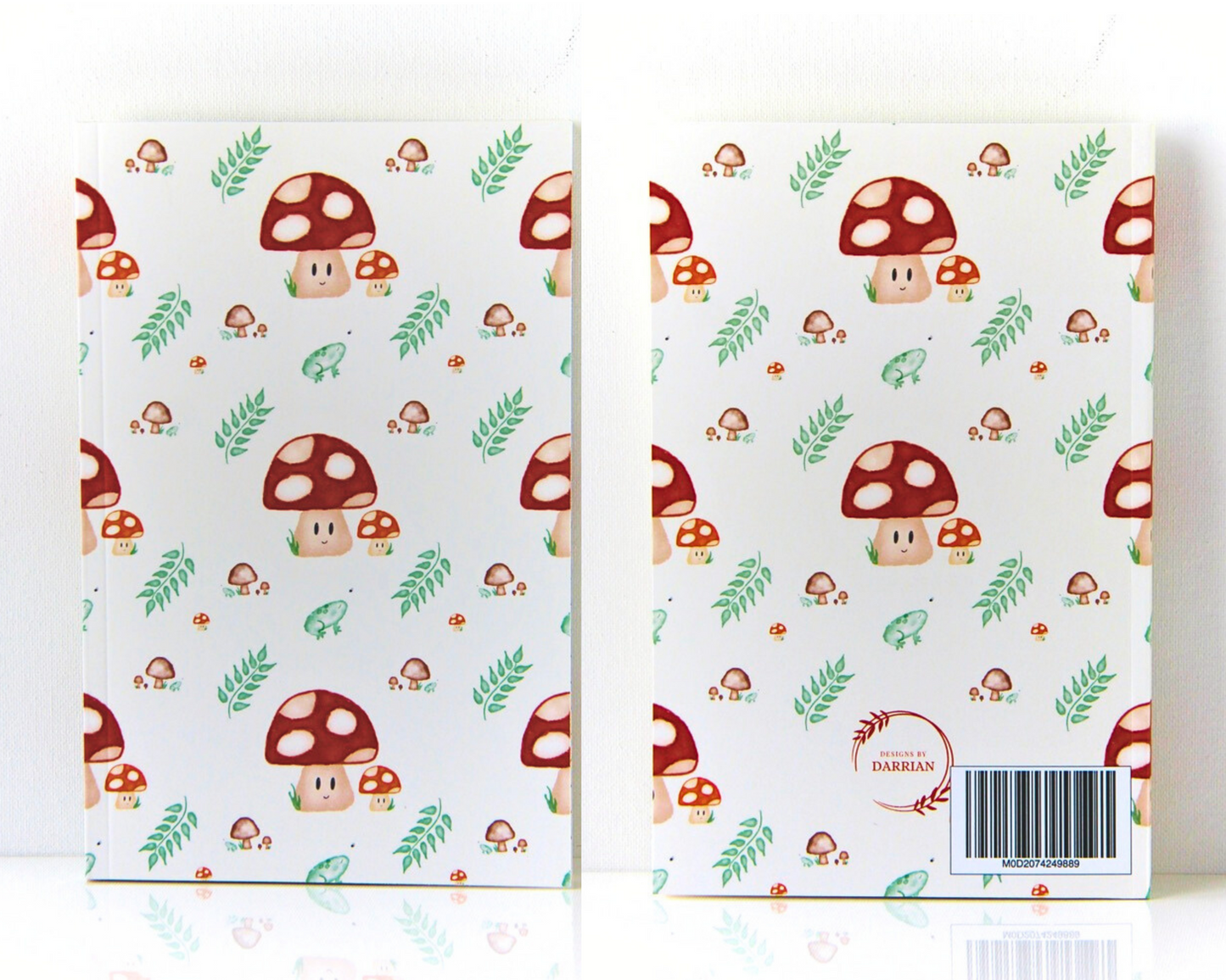 Front and back of a warm white notebook with a cover featuring a watercolour mushroom pattern, the pattern includes smiling spotted mushrooms, brown mushrooms, leaves, and small green frogs.
