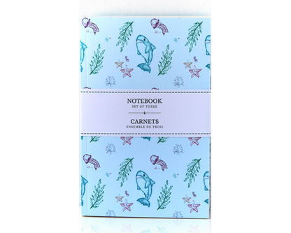 Set of three pastel blue notebooks, watercolour pattern featuring sharks, jellyfish, starfish, shells, and seaweed.