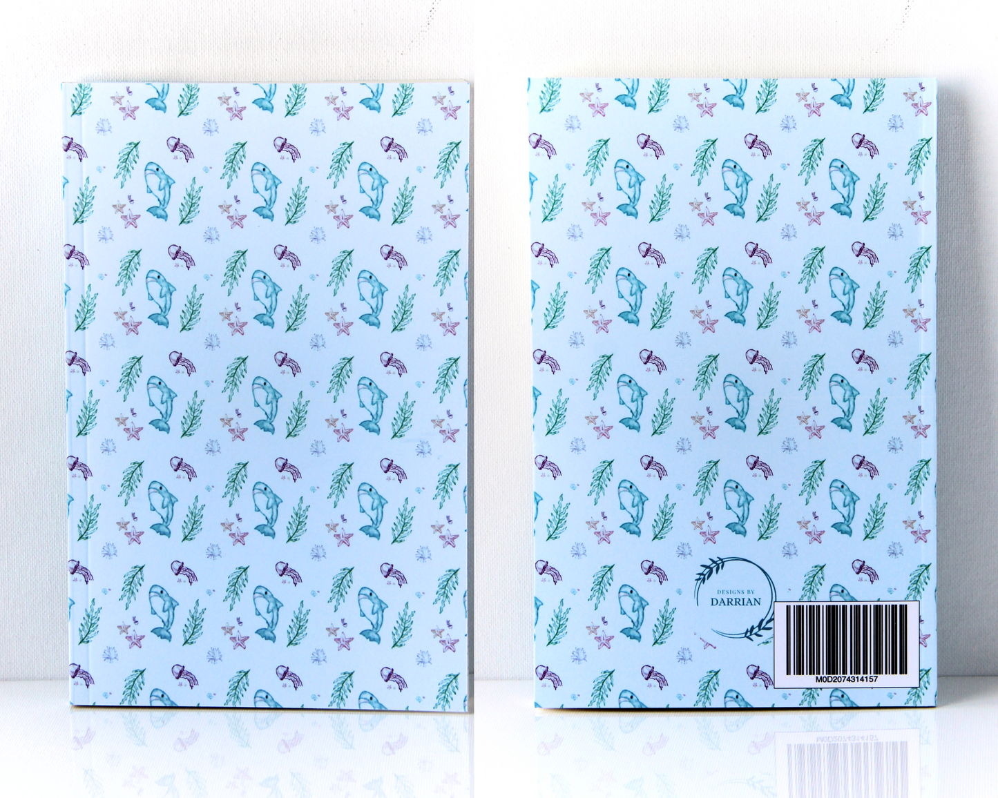 Front and back of a pastel blue notebook with a watercolour pattern featuring sharks, jellyfish, starfish, shells, and seaweed.