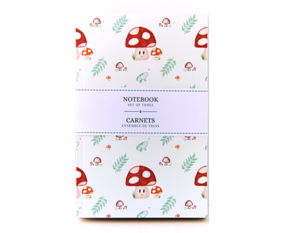 Notebook set of three with a warm white background, with a watercolour pattern featuring red spotted mushrooms, leaves, brown mushrooms, and small green frogs.