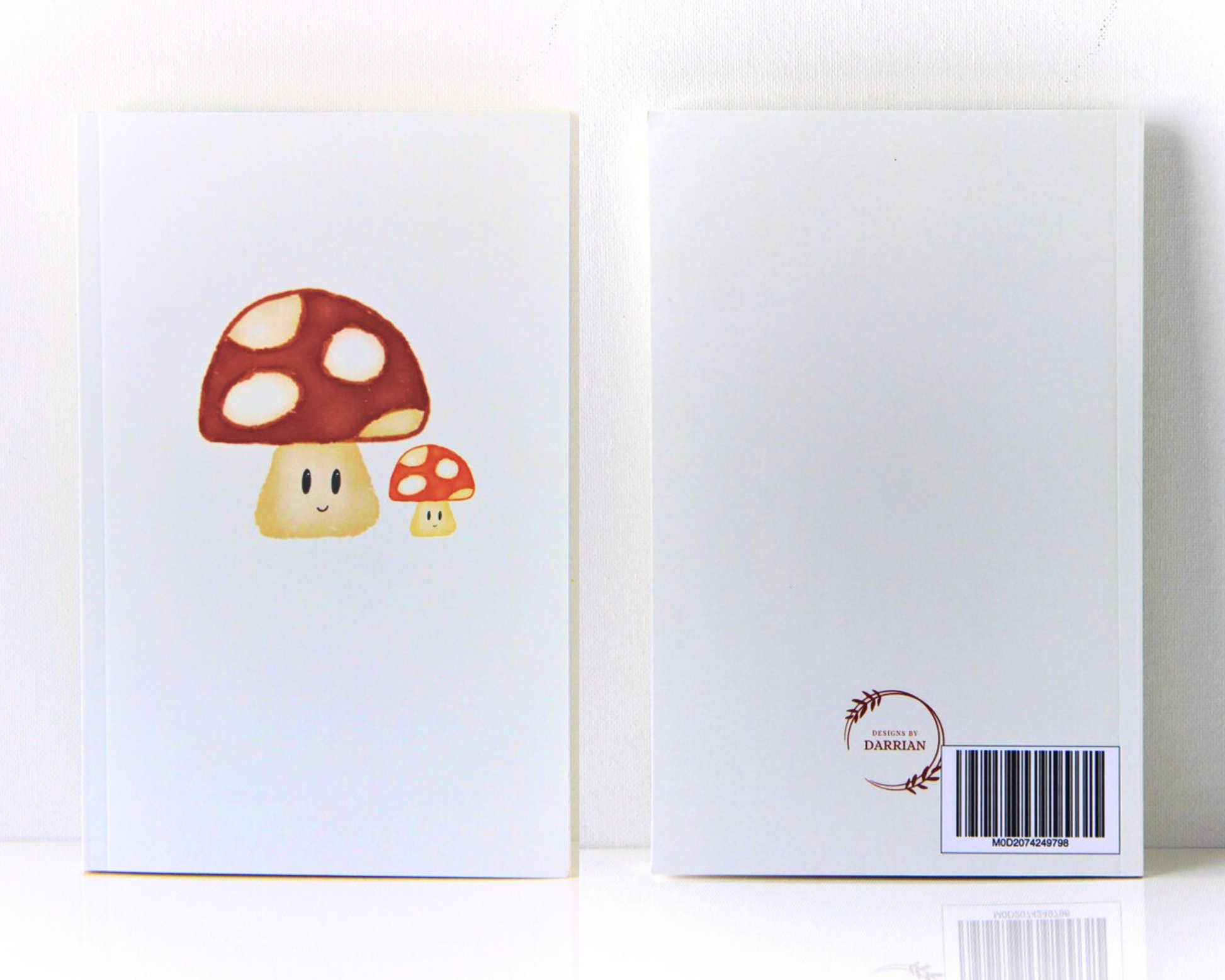 front and back of a warm white notebook featuring two smiling watercolour mushrooms, each have spotted caps in deep red and vibrant orange