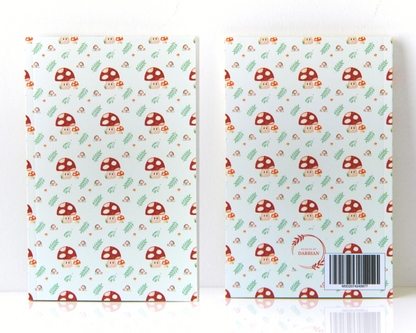 Front and back of a warm white notebook with a cover featuring a watercolour mushroom pattern, the pattern includes smiling spotted mushrooms, brown mushrooms, leaves, and small green frogs. 