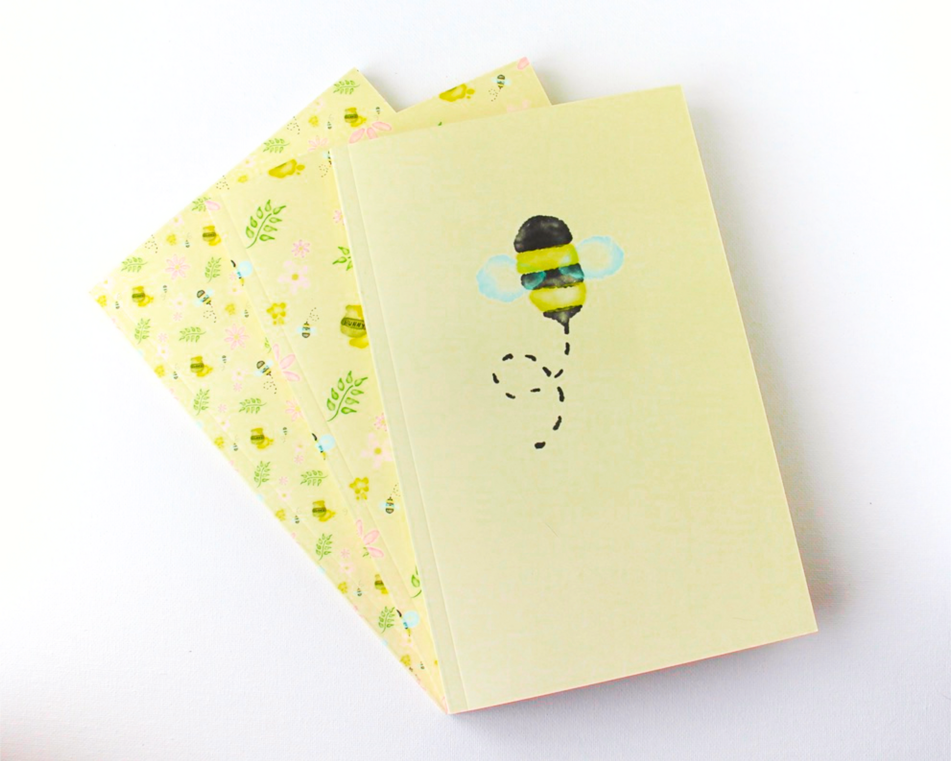 Yellow Pastel Notebook Set of Three with covers featuring watercolour bees, leaves, pink flowers, and honey pots